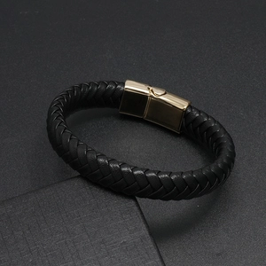 Detail of woven black leather bracelet featuring a polished gold magnetic clasp closure
