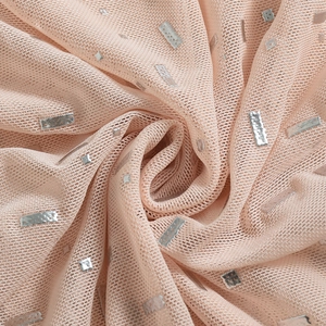 Gros plan sur tissu mesh transparent avec paillettes argentées sur fond rose nude