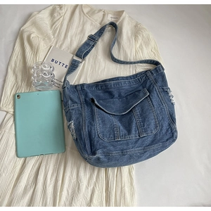 Gros plan sur un sac bandoulière en denim bleu avec bords effilochés et boucles en métal