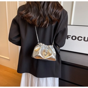 Silver metallic pleated cloud bag with pearl closure and chain strap shown on model