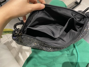 Detail view of the black rhinestone handbag interior with fabric lining and zip pocket
