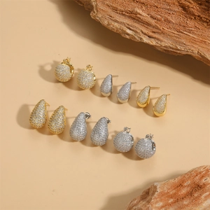 Elegant gold and silver hoop earrings set with zircon pave crystals on minimalist background