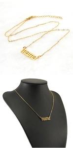 Detail of gold MAMA letter pendant necklace on white fur and mannequin display