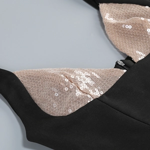 Détail d'une robe noire à paillettes avec col en V profond et empiècements en tulle