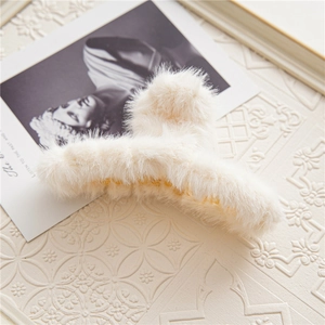 Detail of plush cream faux fur hair claw clip on vintage aesthetic background