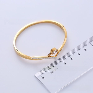 Macro shot of gold-plated V-shaped bangle with crystals and 6cm inner diameter scale
