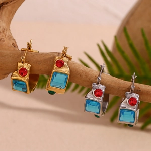 Macro view of vintage style gold and silver earrings with colorful gemstones on a branch