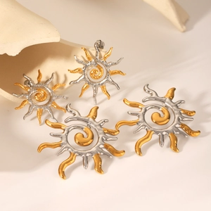 Detailed macro of gold and silver sun flame stud earrings with spiral textured metal finish