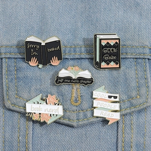 Detailed enamel book pins pinned on blue denim jacket pocket featuring reading quotes