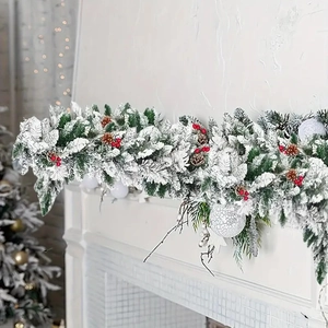 Flocked Christmas garland with red berries and pine cones on a white fireplace mantel