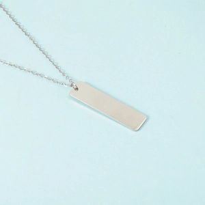 Detail of silver rectangular bar pendant with polished stainless steel finish on chain