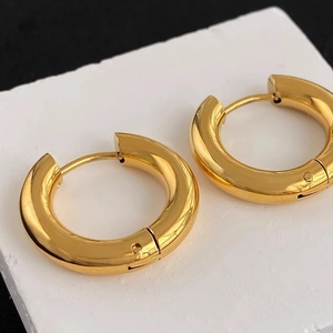 Minimalist chunky golden titanium steel hoop earrings displayed on white stone