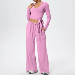 Détail d'un ensemble de yoga rose avec haut court à lacets et pantalon large taille haute