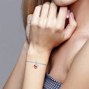 Close-up of silver bracelet with red lipstick charm and heart engraved with kiss