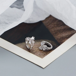 Detail of silver bow earrings with clear cubic zirconia on a vintage photo card