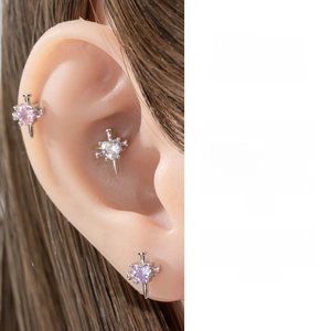 Detail of heart-shaped zircon ear studs in pink, white, and purple on a model ear