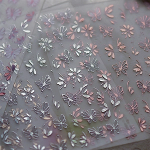 Detailed macro shot of 3D embossed butterfly and floral gold foil nail art stickers
