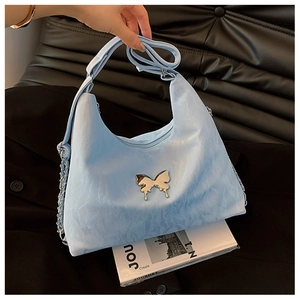 Detailed view of light blue crescent bag with silver butterfly and chain strap accent