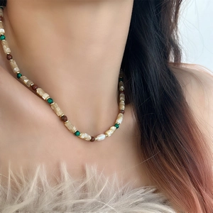 Detail of beaded shell necklace with green malachite and freshwater pearls on model