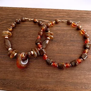 Maillard geometric irregular pendant necklace with tiger eye beads on wood background