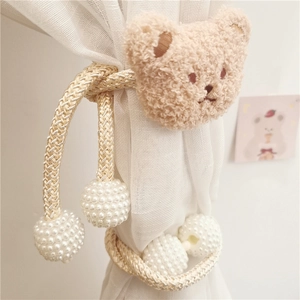 Close-up of khaki plush bear curtain tieback with faux pearls on white mesh curtain
