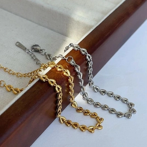 Detailed close-up of 18k gold and silver heart-shaped braided bracelets in a jewelry tray