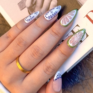 Detailed view of almond press-on nails with blue floral patterns and 3D floral accents