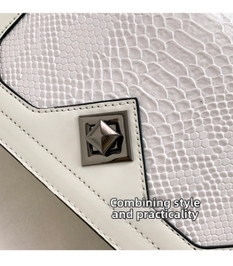 Detail of white crocodile texture leather bag with silver metal pyramid square lock