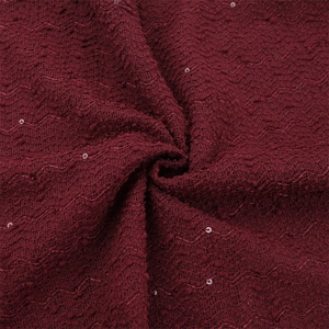 Détail du tissu tricoté bordeaux avec paillettes montrant un drapé élégant et chic