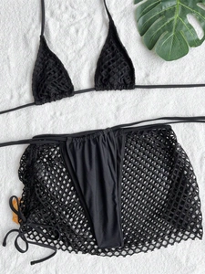 Detailed flat lay of a black three-piece bikini set with a matching mesh sarong and leaf decor