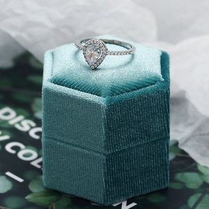 Macro shot of silver pear-cut zircon ring on a green velvet hexagonal jewelry box