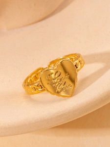 Detailed macro view of gold heart ring with Love You engraving and Cuban chain band