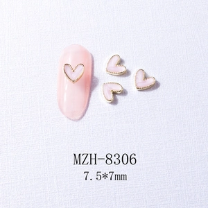 Pink heart nail charm with gold metal edging and dimensions 7.5x7mm on a textured cloth