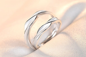 Macro shot of couple rings with crown zircon details on romantic champagne silk fabric