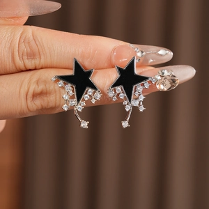 Macro view of black star stud earrings with clear zircon tassels and silver needle