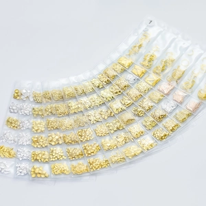Assorted gold and silver metal nail art charms in a professional six-grid bag set