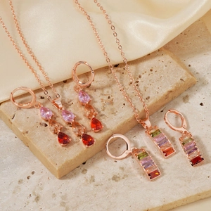 Parure de bijoux en or rose avec pierres précieuses colorées sur pierre beige et soie
