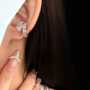 Primo piano di un ear cuff a forma di serpente argento con zirconi su un orecchio