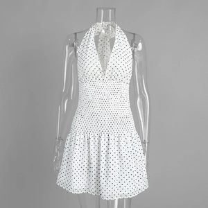 Detail of the smocked elastic waist and polka dot pattern on a white halter dress