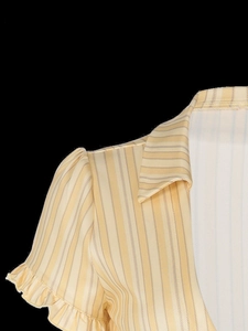 Détail d'une chemise à rayures jaunes avec manches bouffantes, col polo et poignets volantés