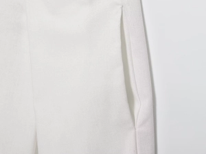 Detail of the white woven fabric texture and structured side pocket on bomber trousers