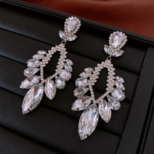 Close-up of bohemian hollow drop earrings with clear faceted crystals and silver plating
