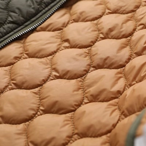 Macro view of olive green shell with brown round quilted lining on a padded jacket