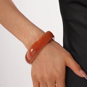 Close-up of a polished amber resin geometric bangle with a smooth translucent finish