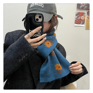 Detailed texture of thick navy knit scarf with orange floral pattern on female model
