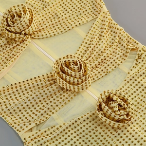 Détail macro du tissu en maille jaune avec strass dorés et fleurs de roses en 3D
