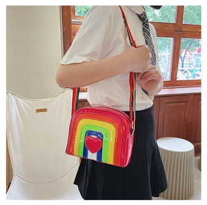 Rainbow crossbody bag with heart patch and wide fabric strap in a bright indoor setting