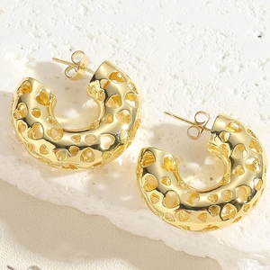 Detailed close-up of golden C-shaped hoop earrings with hollow heart-shaped cutouts