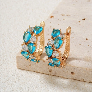 Macro detail of luxury vintage gold earrings with blue water-drop gems and white zircons