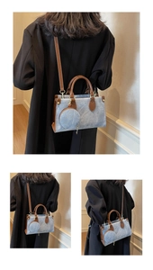 Détail du cabas en denim bleu avec anses en cuir marron et petit porte-monnaie rond